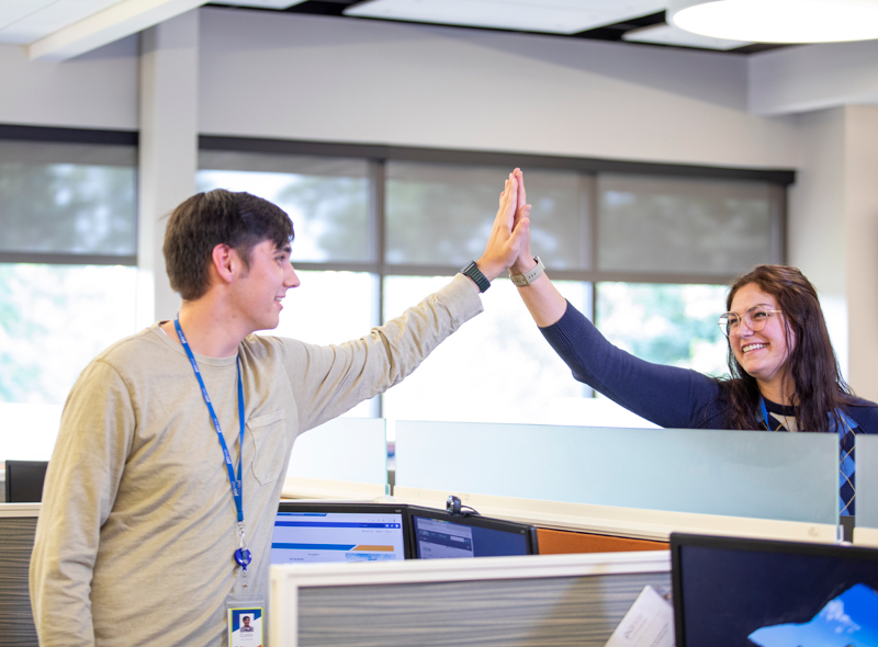 Two female PCI employees in office high fiving<br />
