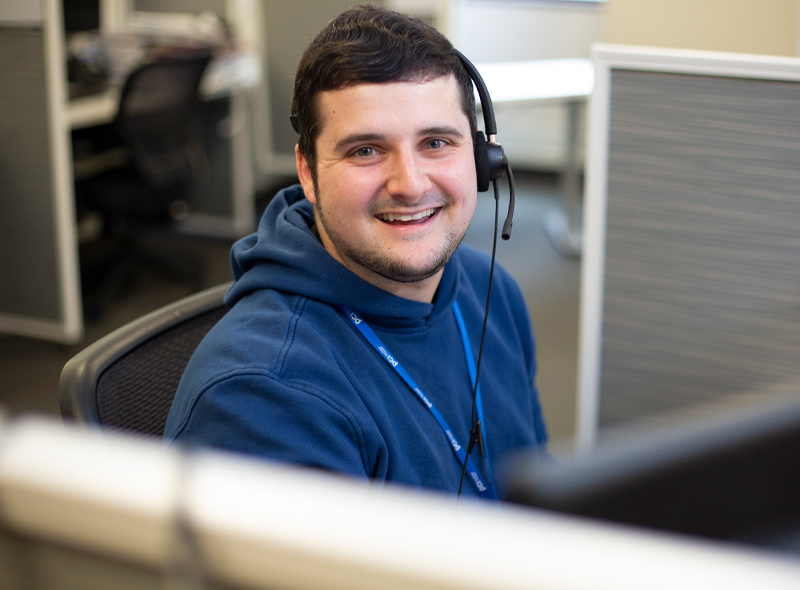 Employee wearing blue hoodie looking at camera and smiling