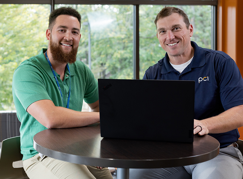 Two employees sitting at table with laptop